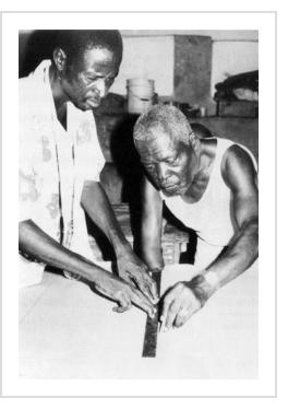 Ceus "Tibout" St. Louis working with his son-in-law Luc Cedor, 1993 (photo by Tina Girouard in Sequin Artists of Haiti))